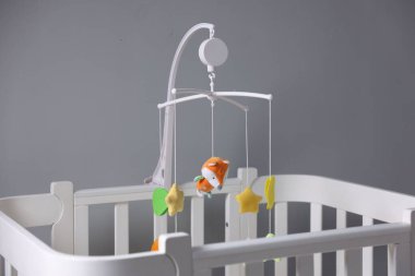 Çocuk odasındaki gri duvarın yanında şirin bebek arabası olan bir beşik.