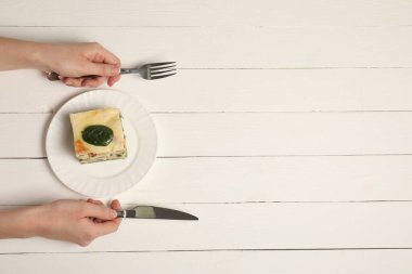 Beyaz ahşap masada, nefis ıspanaklı lazanya yiyen bir kadın. Metin için boşluk