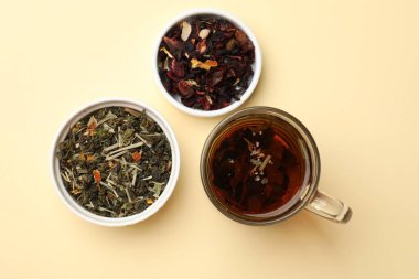 Aromatik çay ve kurutulmuş yapraklar bej arka planda, düz uzanmış