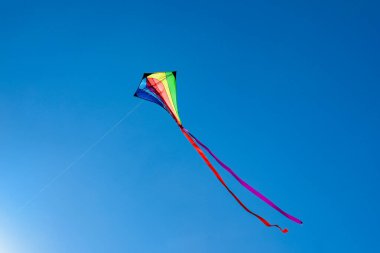Mavi gökyüzünde uçan renkli bir uçurtma