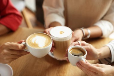 Kafedeki ahşap masada bir fincan lezzetli kahve içen kadınlar, yakın plan.