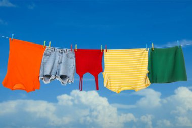 Different clothes drying on washing line against blue sky