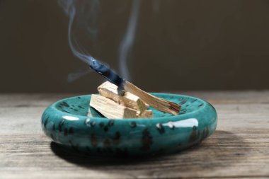 Palo santo sopaları ve yanan bir tahta masa üzerinde gri arka plan, yakın çekim