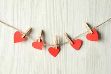 Sevgililer Günü. Beyaz ahşap arka planda asılı kağıt kalpli bir ip.