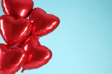Açık mavi arka planda bir sürü kırmızı kalp şeklinde balon, yazı için boşluk. Sevgililer Günün kutlu olsun.