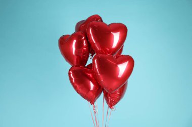 Açık mavi arka planda bir sürü kırmızı kalp şeklinde balon. Sevgililer Günün kutlu olsun.