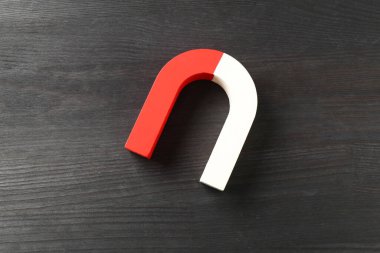 Siyah ahşap zemin üzerinde bir at nalı mıknatısı, üst manzara.