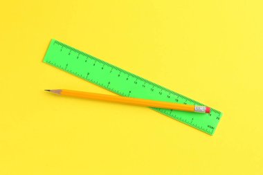 Sarı arkaplanda cetvel ve kalem, üst görünüm