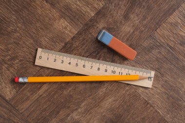 Cetvel, kalem ve silgi tahta masada, düz yatıyordu.