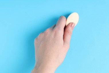 Açık mavi arkaplanda silgi kullanan kadın, yakın plan