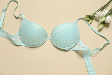 Güzel turkuaz sütyen ve bej arka planda çiçekler, düz uzanmış.