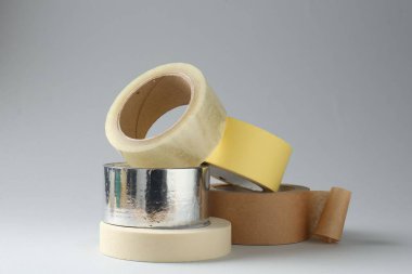 Gri arkaplanda farklı yapışkan bantların ruloları