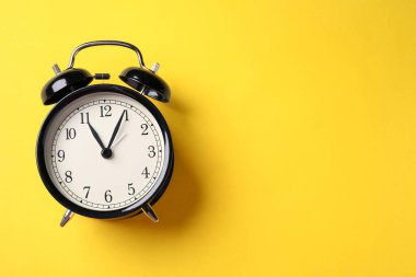 Sarı arka planda siyah alarm saati, üst manzara. Metin için boşluk