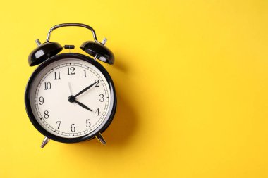 Sarı arka planda siyah alarm saati, üst manzara. Metin için boşluk