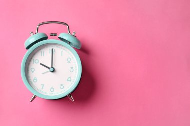 Pembe arka planda turkuaz alarm saati, üst manzara. Metin için boşluk