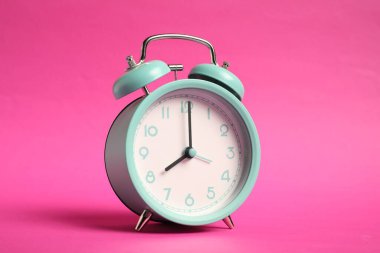 Parlak pembe arka planda bir turkuaz alarm saati