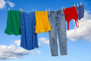 Different clothes drying on washing line against blue sky