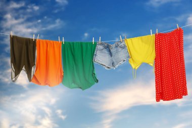 Different clothes drying on washing line against blue sky