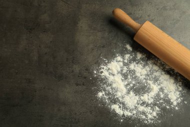 Gri masa üzerinde ahşap merdane ve un, üst manzara. Metin için boşluk
