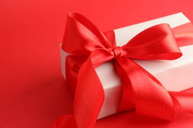 Kırmızı arka planda güzel bir fiyonk olan hediye kutusu