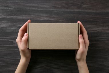 Koyu ahşap arka planda, boş karton kutulu kadın, üst manzara. Tasarım için model