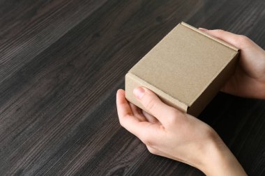 Karanlık ahşap arka planda boş karton kutulu bir kadın, yakın plan. Tasarım için model