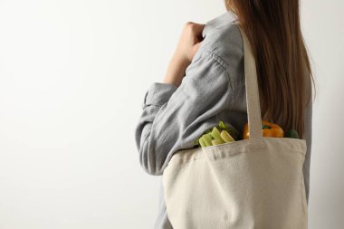 Beyaz arka planda alışveriş torbası taşıyan bir kadın, yakın plan ve mesaj için yer. Çevre dostu yaşam tarzı