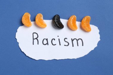 Card with word Racism and tangerine segments of different colors on blue background, top view clipart