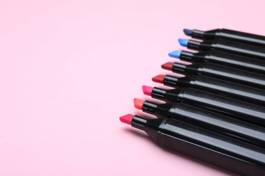 Açık pembe arka planda renkli işaretler, yakın plan. Metin için boşluk