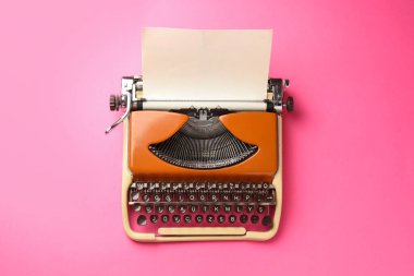 Pembe zemin üzerinde kağıt yaprağı olan klasik daktilo, üst görünüm