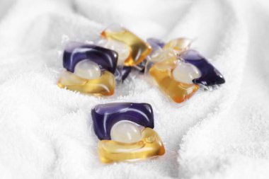 Çamaşır deterjanı kapsülleri beyaz havluda, yakın plan.