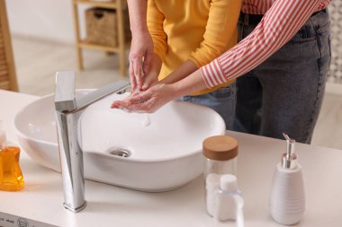 Anne ve kız ellerini lavabonun üstünde yıkıyor, kapalı.