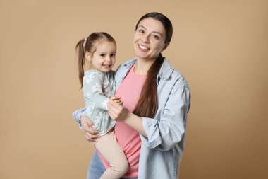 Bej arka planda mutlu anne ve tatlı kızının portresi.