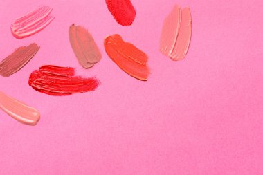Pembe arka planda farklı dudak ürünleri örnekleri, üst manzara. Metin için boşluk