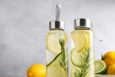 Biberiyeli limon suyu ve açık gri arka planda taze meyveler, yakın plan. Metin için boşluk