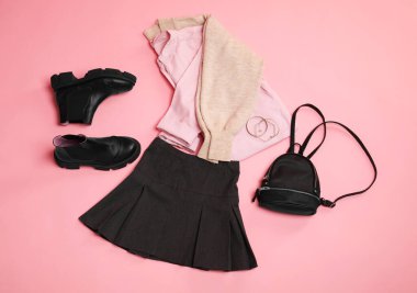 Pembe arka planda şık elbiseler, botlar ve aksesuarlar, düz yatış.