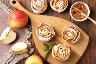 Ahşap masada servis edilen pudra şekerli lezzetli elma gülleri.