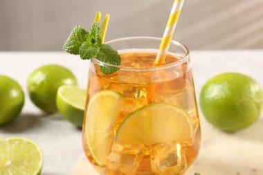 Buzlu çayı limon dilimleriyle, nane şekeriyle ve cam bardakta saman içerek, yakın plan.