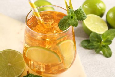 Buzlu çayı limon dilimleriyle, nane şekeriyle ve cam bardakta saman içerek, yakın plan.
