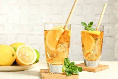 Buzlu çayı pipetle tazelemek, nane ve limon yeşil arka planda hafif desenli masada, yakın plan