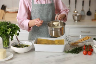 Mutfaktaki mermer masada ıspanaklı lazanya yapan kadın, yakın plan.