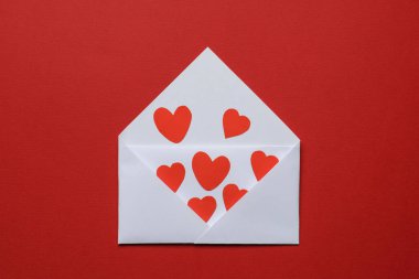 Sevgililer Günü. Kırmızı arkaplanda birçok kağıt kalpli zarf, üst görünüm