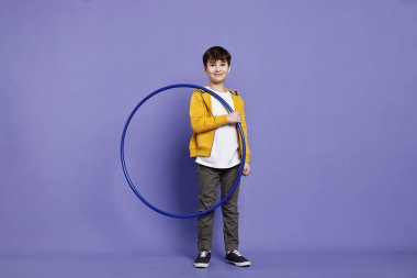 Smiling boy with hula hoop on violet background clipart