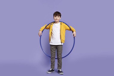 Boy with hula hoop on violet background clipart