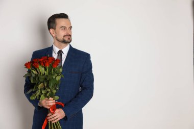 Sevgililer Günün kutlu olsun. Beyaz arka planda gül buketi olan yakışıklı bir adam. Metin için boşluk