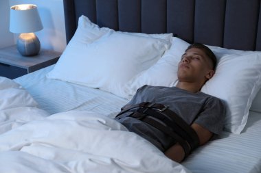 Uyurgezer yatağa uzanmış kemerlerle bağlı