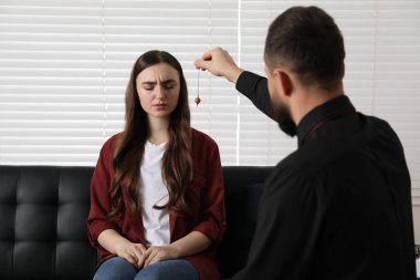 İçeride hipnoz seansı sırasında hastayla çalışırken sarkacı kullanan psikolog.