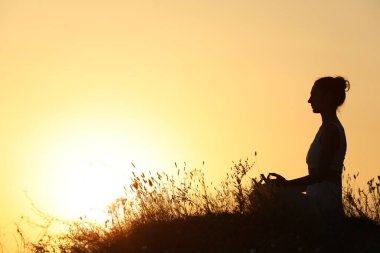 Gün batımında dışarıda meditasyon yapan kadın silueti. Metin için boşluk