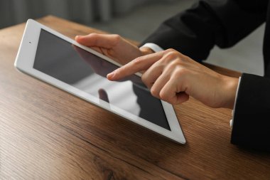 İş kadını, kapalı bir masada tablet kullanıyor, yakın plan. Modern teknoloji