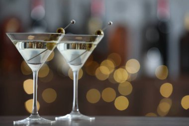 Ahşap masada zeytinli martini kokteyli, arka planda bulanıklık, yakın plan. Bokeh etkisi